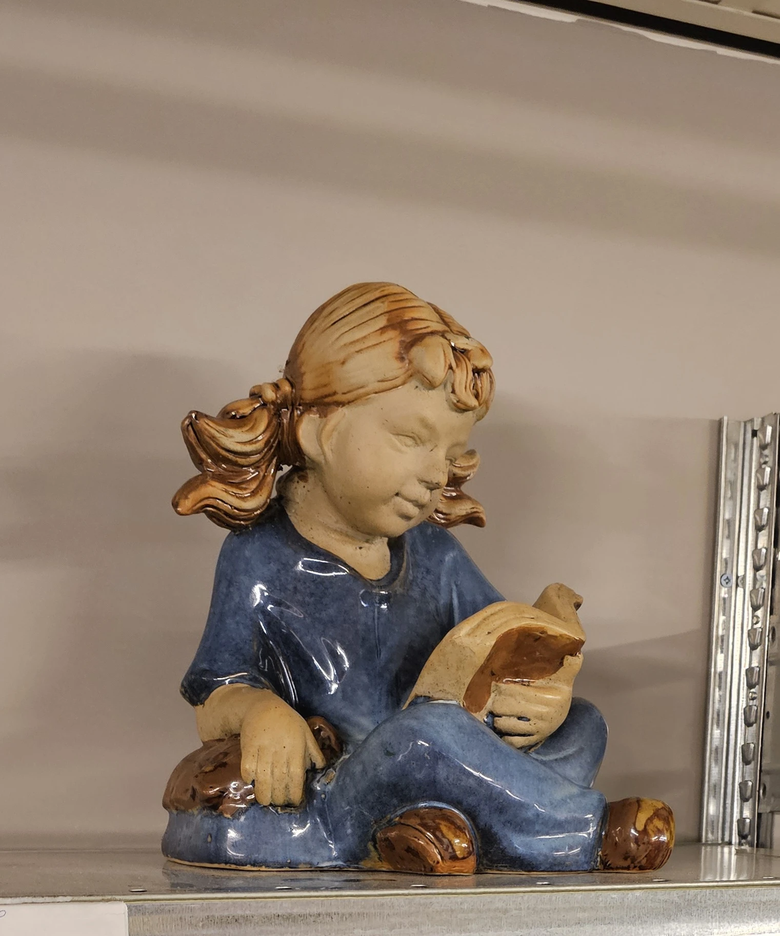 Houten beeldje van een meisje in blauwe jurk met gouden haar, close-up