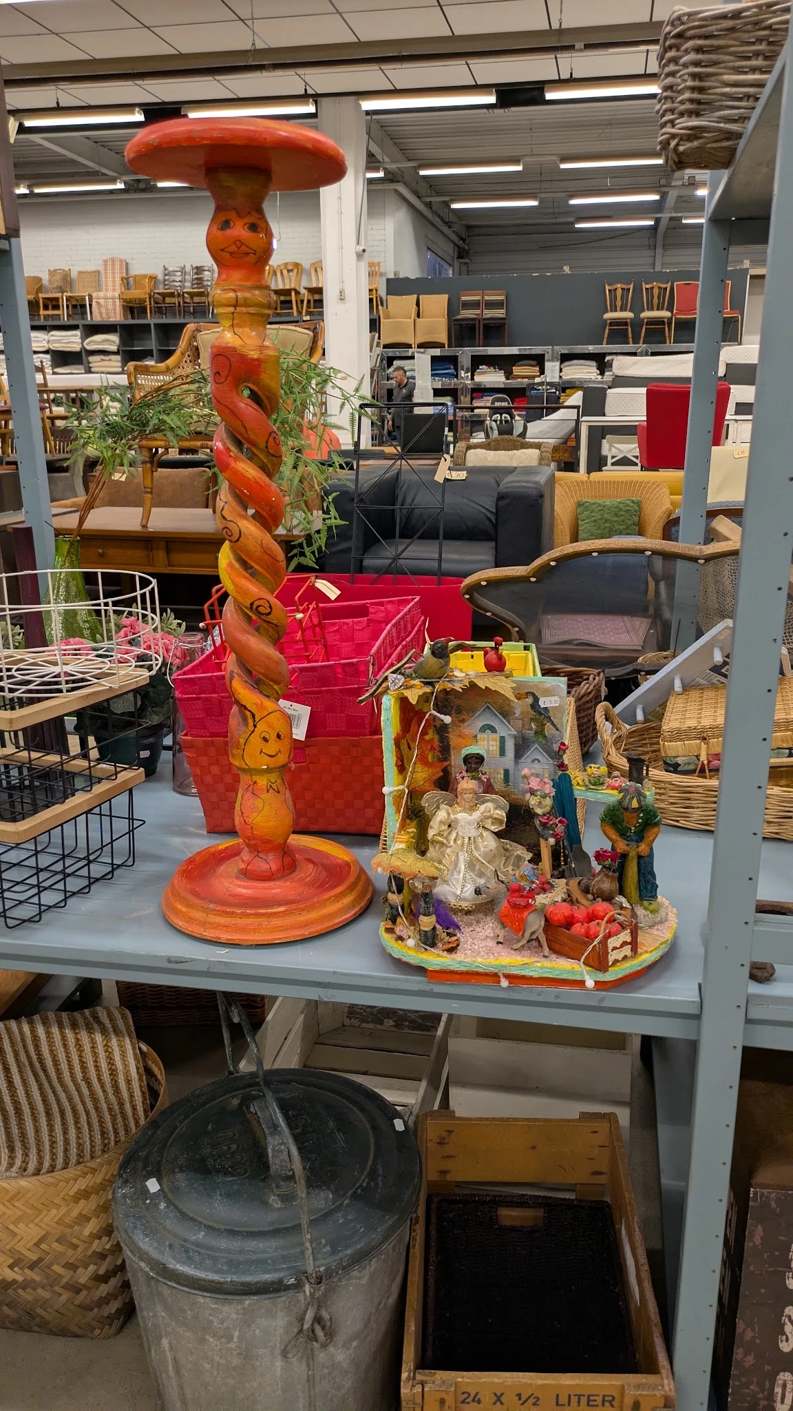 Uitgestalde decoratieve items in een kringloopwinkel: een houten spiraalvormig object, rode dozen, een kerststal en diverse h