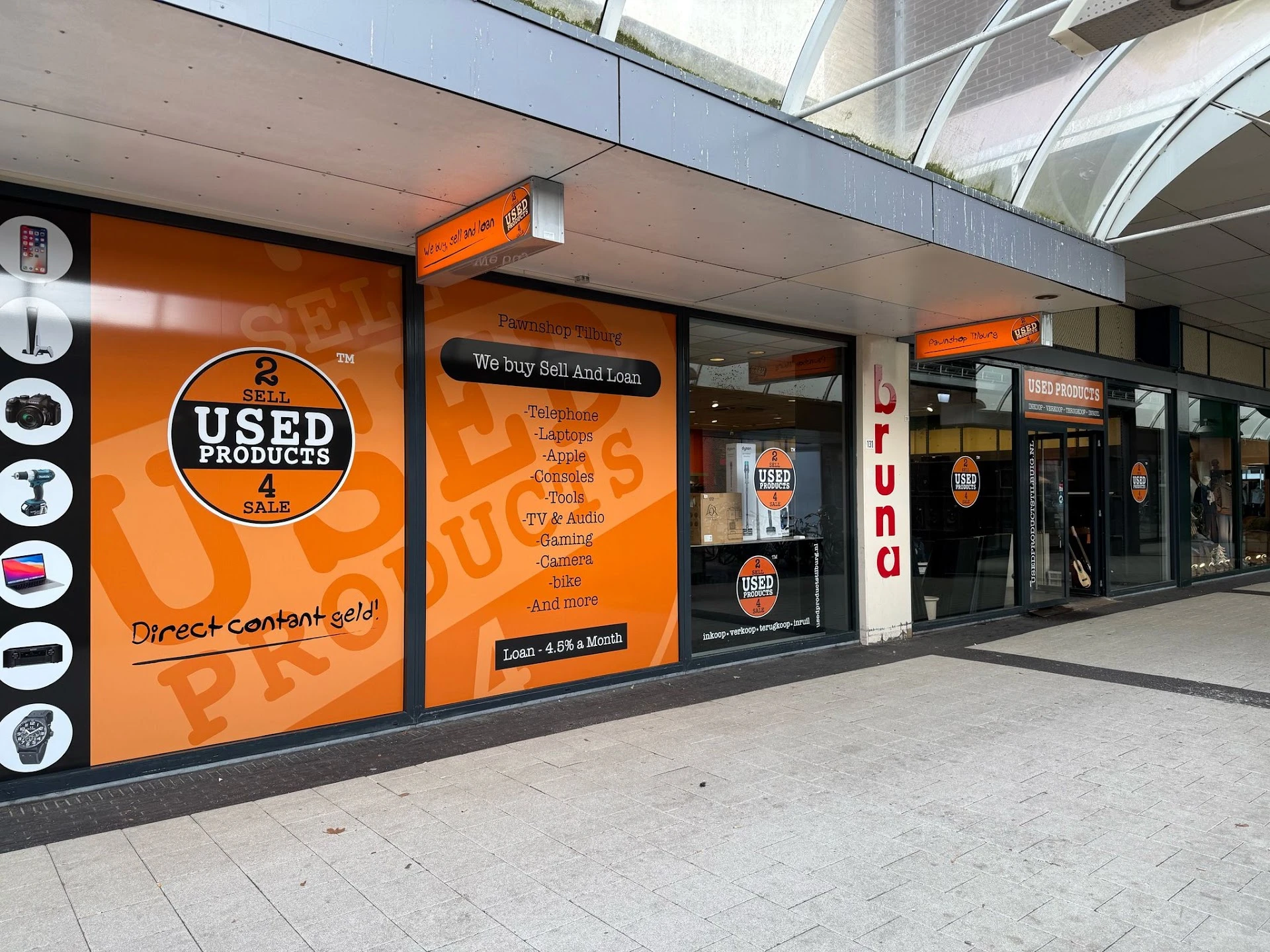 Winkelpui van kringloopwinkel met oranje gevel, rondlogo 'USED PRODUCTS' en tekst 'We buy Sell And Loan'