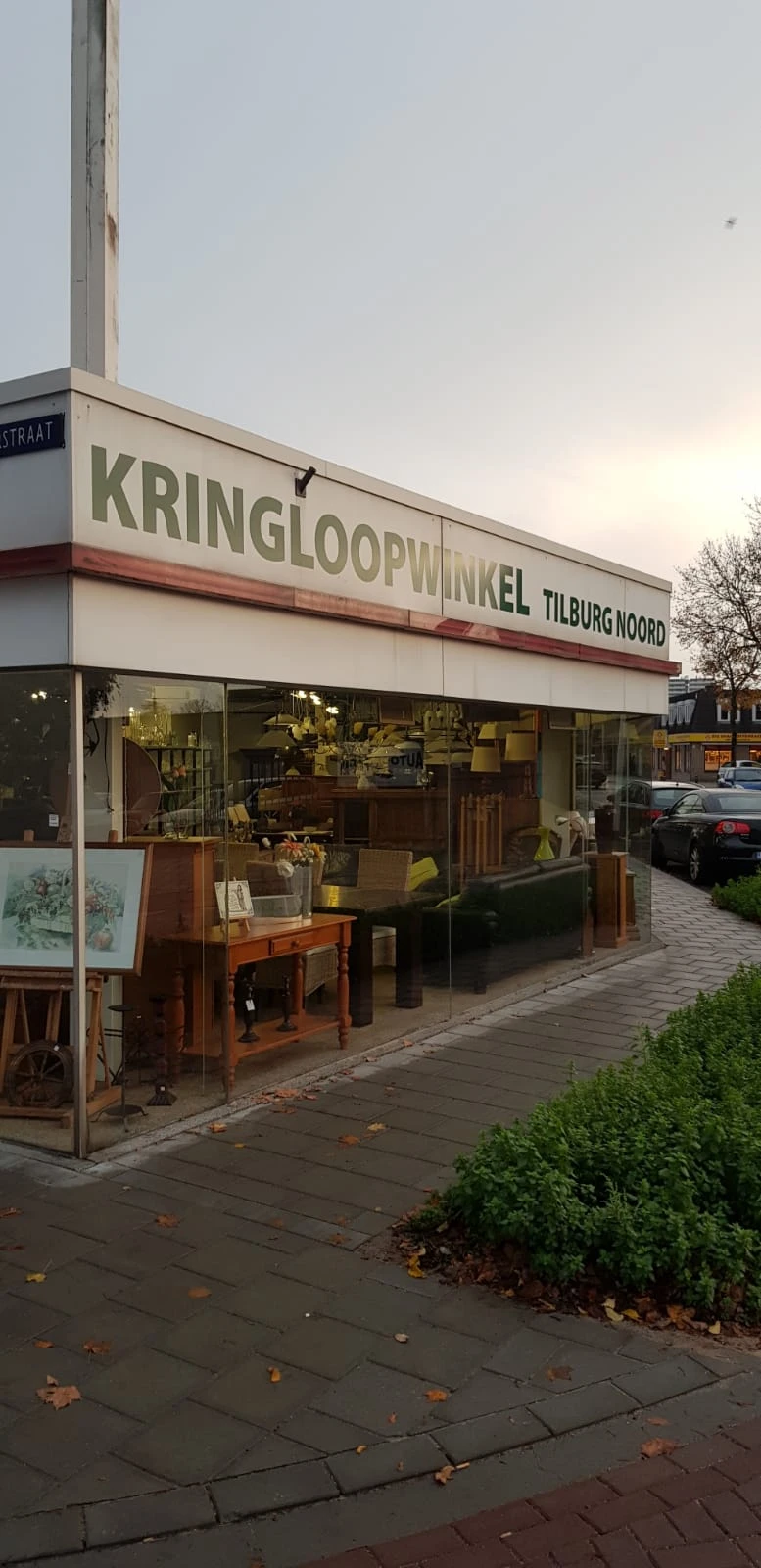 Gevel van kringloopwinkel Tilburg Noord met grote ramen waarachter meubelen en huishoudartikelen zichtbaar zijn