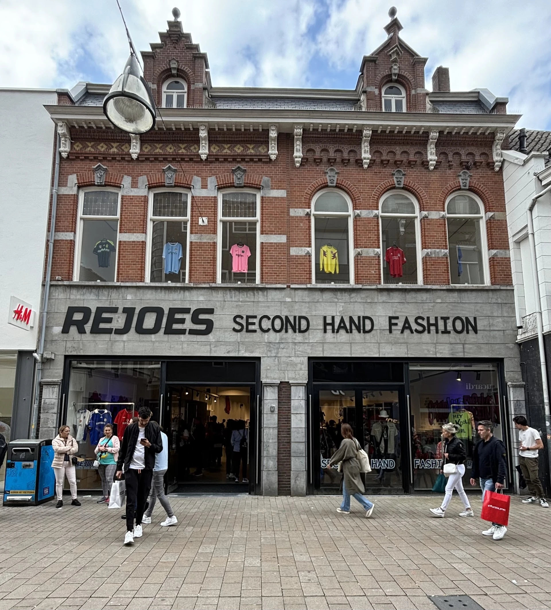 Gevel van tweedehands modezaak REJOES met grote etalageruiten en winkelentree aan een winkelstraat