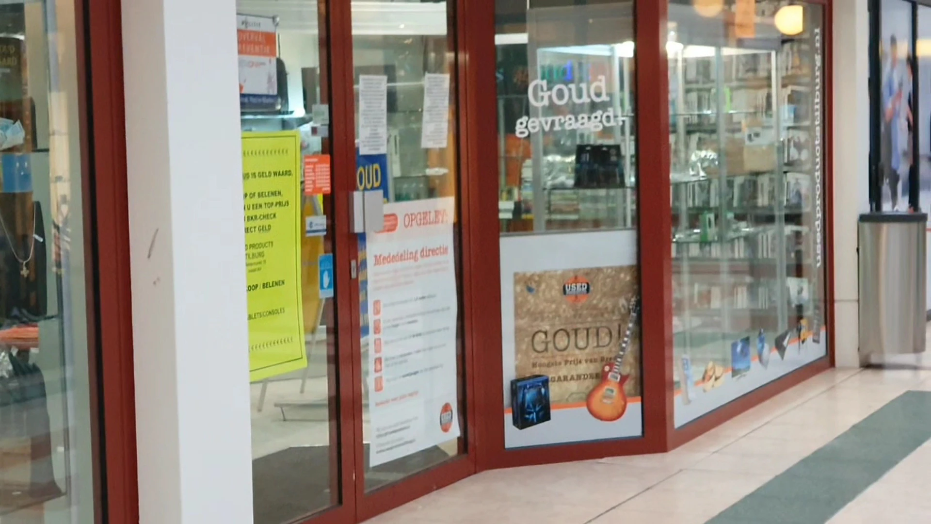 Winkelruit met rode kozijnen, posters en reclame in het glas