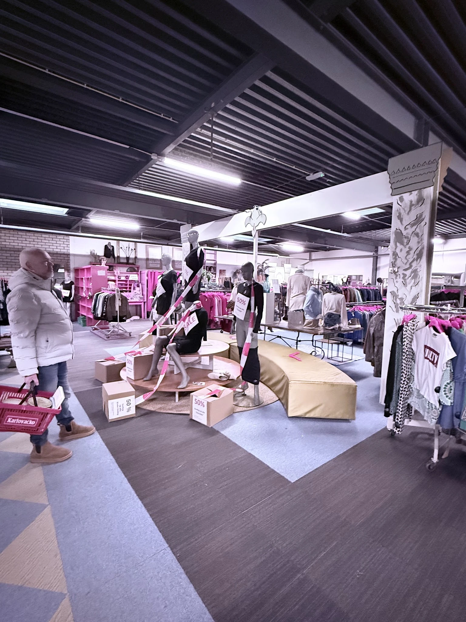 Winkelvloer met kledingrekken, mannequins en dozen in een kringloopwinkel met industrieel plafond