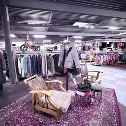 Winkelvloer met kledingrekken, zithoeken met stoelen en fietsen aan het plafond