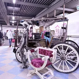 Winkelinterieur met een decoratieve zwarte paardenbeeldhouwwerk en een roze prinsessenwagen op wielen, omgeven door kledingre