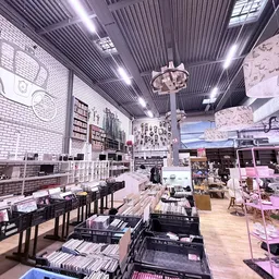 Overzicht van kringloopwinkel met stellingen, display-items, zwarte bakken met spullen en verlichting aan het plafond