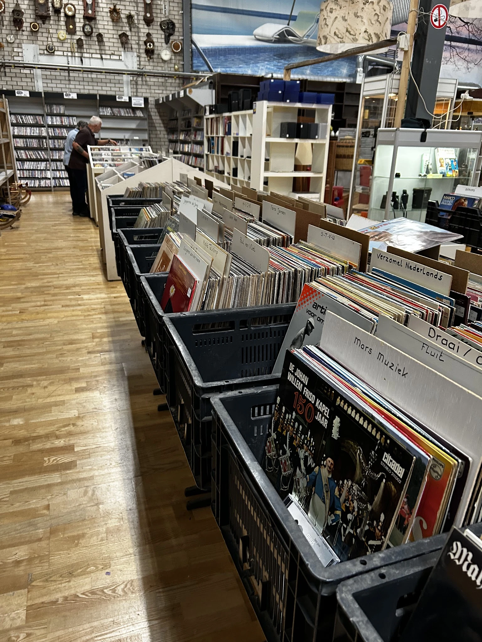 Zwarte winkelrekken met cd's en vinyl records uitgestald in een kringloopwinkel