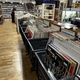 Zwarte winkelrekken met cd's en vinyl records uitgestald in een kringloopwinkel