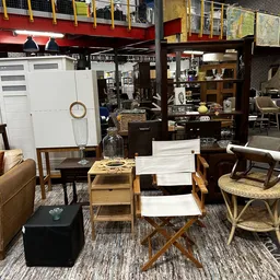Winkelvloer met meubels: stoelen, tafels, kasten en decoratieve items uitgestald in een kringloopwinkel