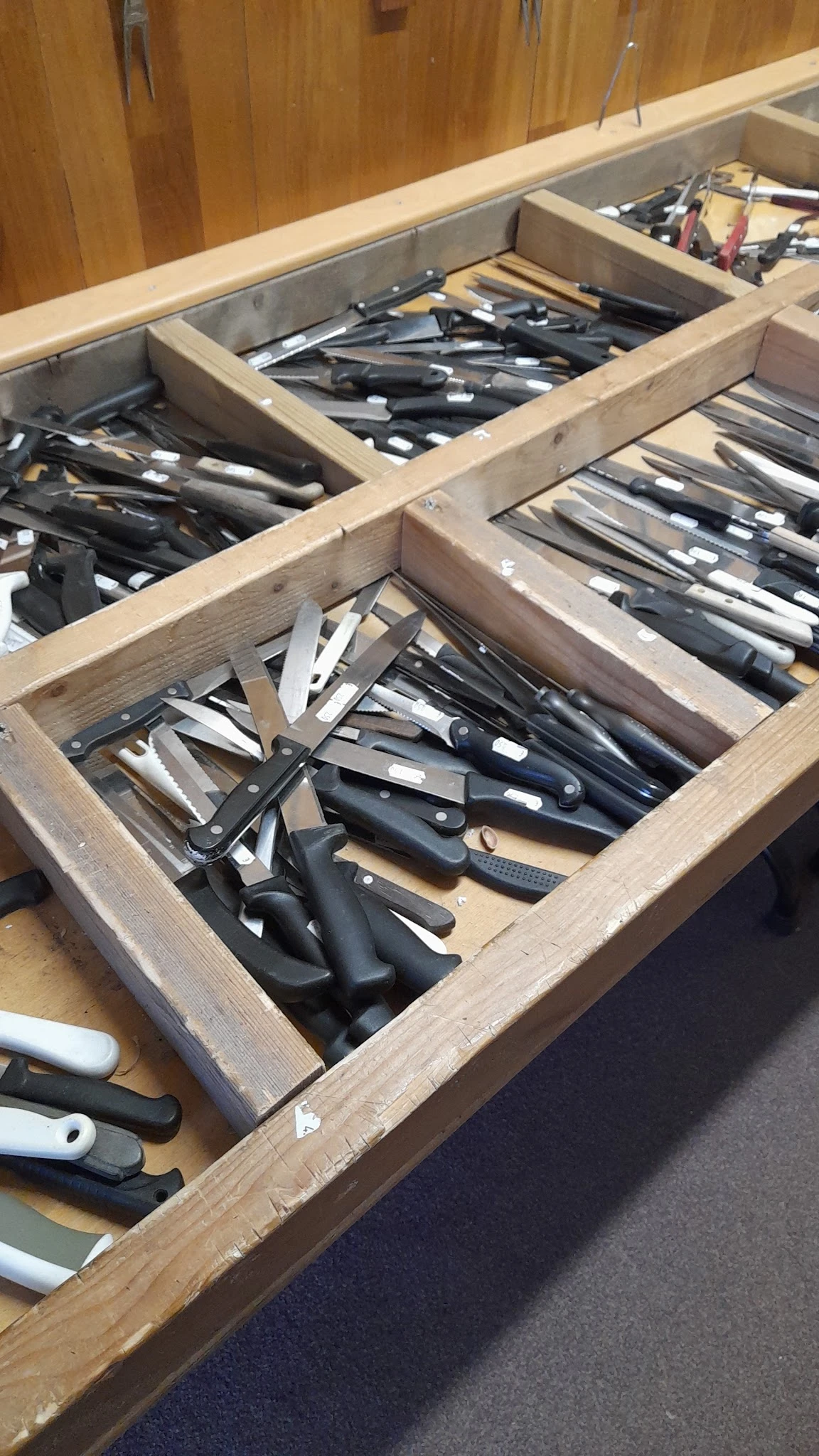 Houten kist met diverse messen en keukengerei netjes uitgestald