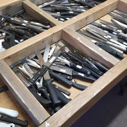 Houten kist met diverse messen en keukengerei netjes uitgestald