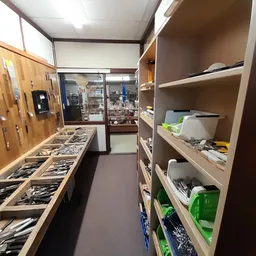 Winkelinterieur met houten stellingkasten vol met artikelen en spullen, zicht op gangpad en display aan de achterwand