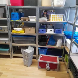 Stellingen met diverse opbergdozen, manden en kunststof bakken in verschillende kleuren