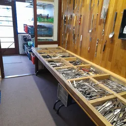 Lange houten tafel met houten bakken vol gereedschap en hardware artikelen