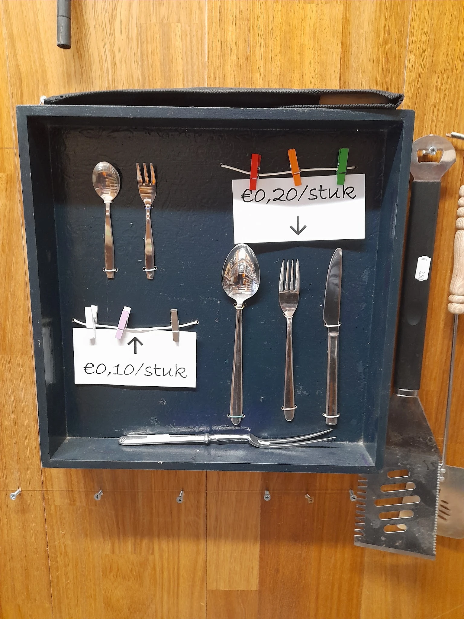 Uitgestalde bestek en lepels met prijskaartjes in een vitrinekast