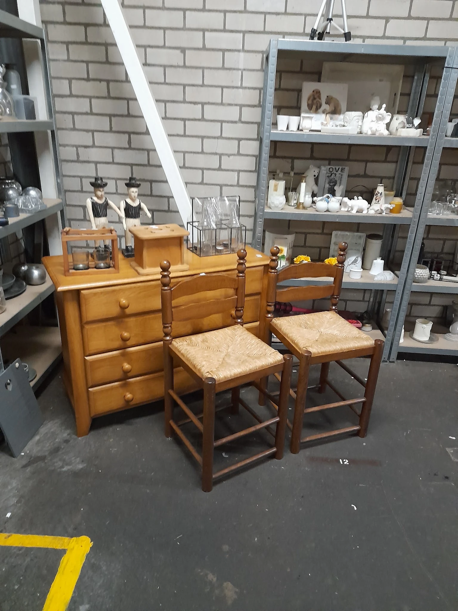 Houten dressoir met drie laden en twee houten stoelen met rieten zitting in kringloopwinkel