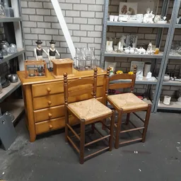 Houten dressoir met drie laden en twee houten stoelen met rieten zitting in kringloopwinkel