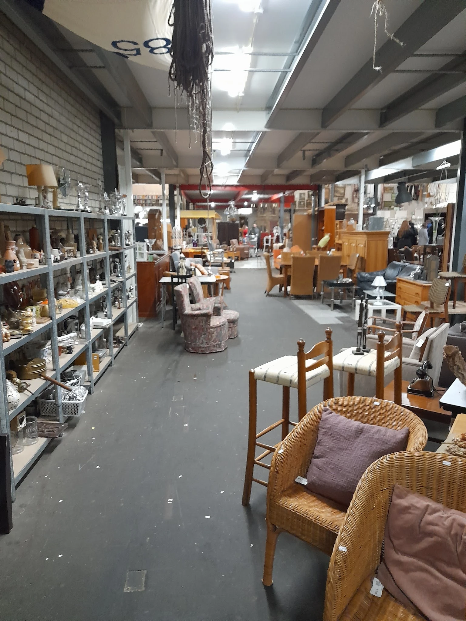 Winkelvloer van kringloopwinkel met stellingen, meubels en huisraad uitgestald