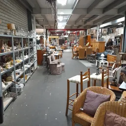 Winkelvloer van kringloopwinkel met stellingen, meubels en huisraad uitgestald