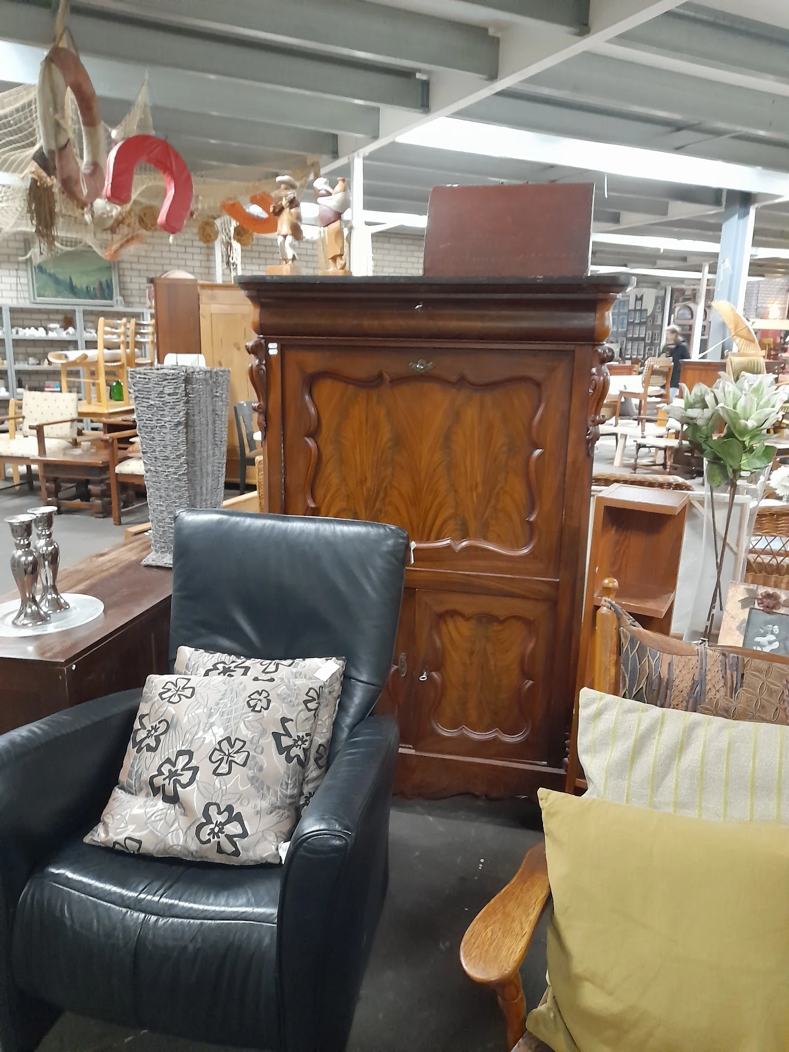 Tweedehandsmeubels in winkel: houten kast, zwarte leunstoel en andere inrichtingsspullen
