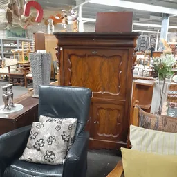 Tweedehandsmeubels in winkel: houten kast, zwarte leunstoel en andere inrichtingsspullen
