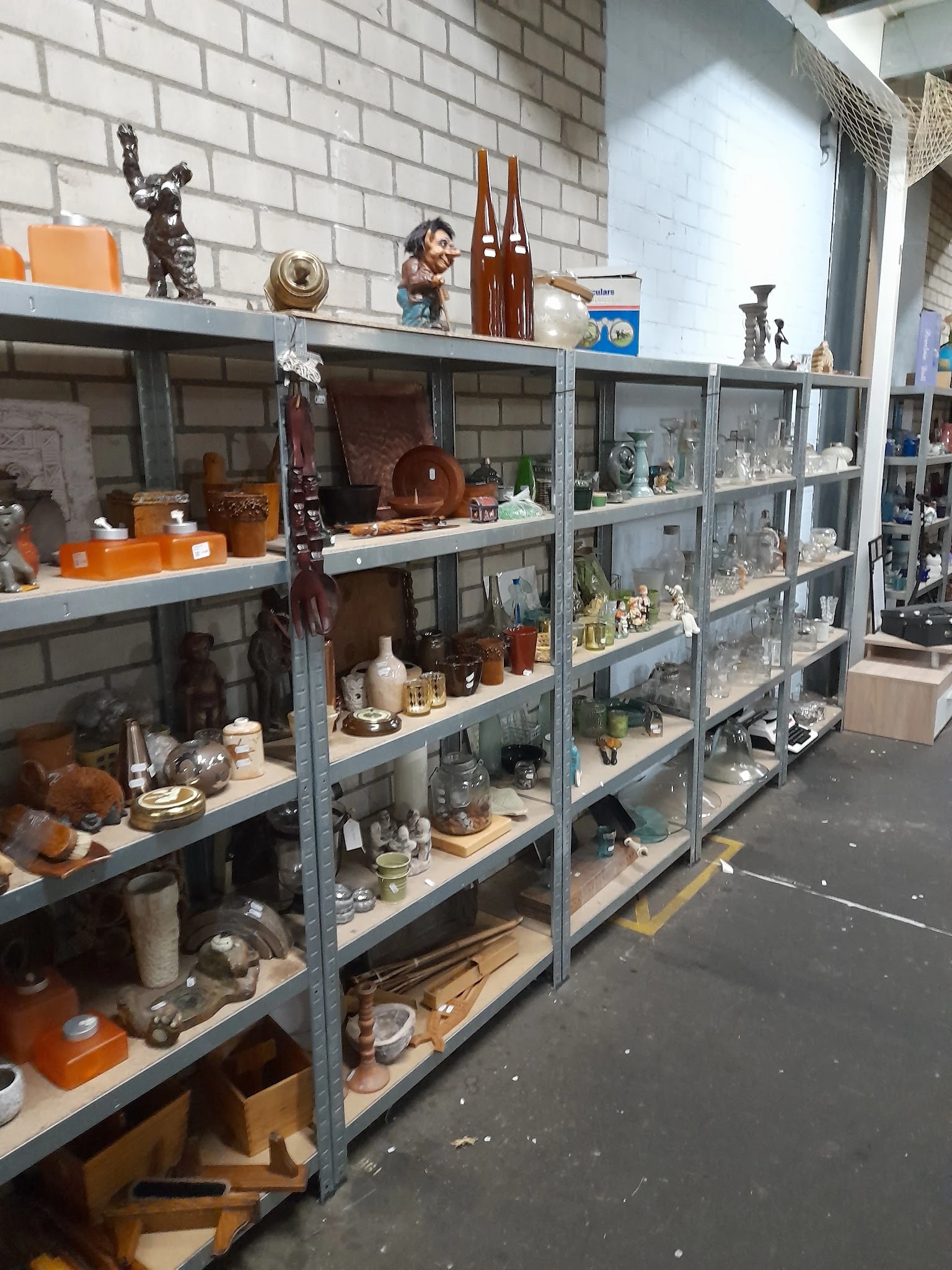 Stellingen met diverse tweedehands huishoudartikelen, servies, decoratie en voorwerpen