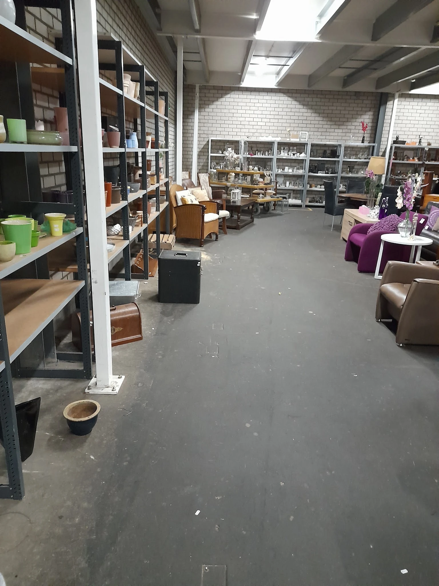 Ruim winkelbinnenland met stellingen, meubels en huishoudartikelen langs de muren en in het midden