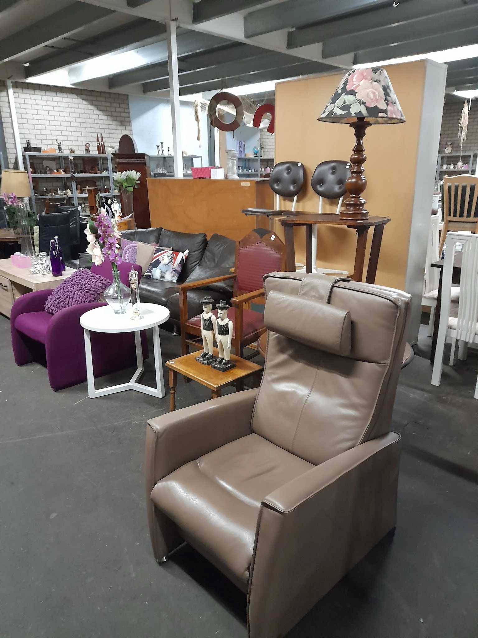 Inrichting van kringloopwinkel met zithoeken, fauteuils, decoratieve objecten en meubels op de vloer