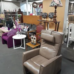 Inrichting van kringloopwinkel met zithoeken, fauteuils, decoratieve objecten en meubels op de vloer