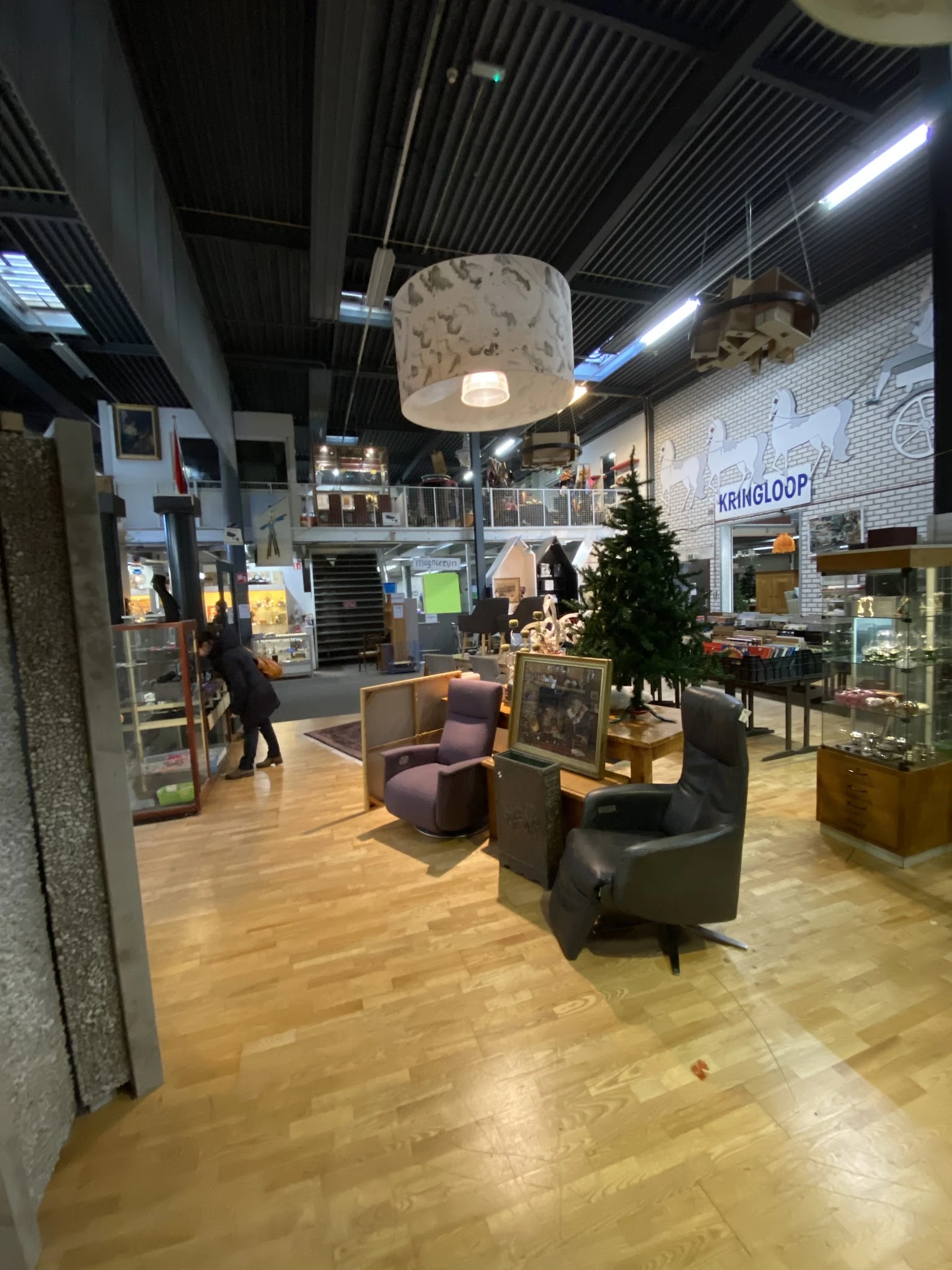 Winkelinterieur met zithoeken, verlichte hanglamp, stellingen met artikelen en uitzicht op meerdere winkelafdeling