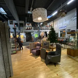 Winkelinterieur met zithoeken, verlichte hanglamp, stellingen met artikelen en uitzicht op meerdere winkelafdeling
