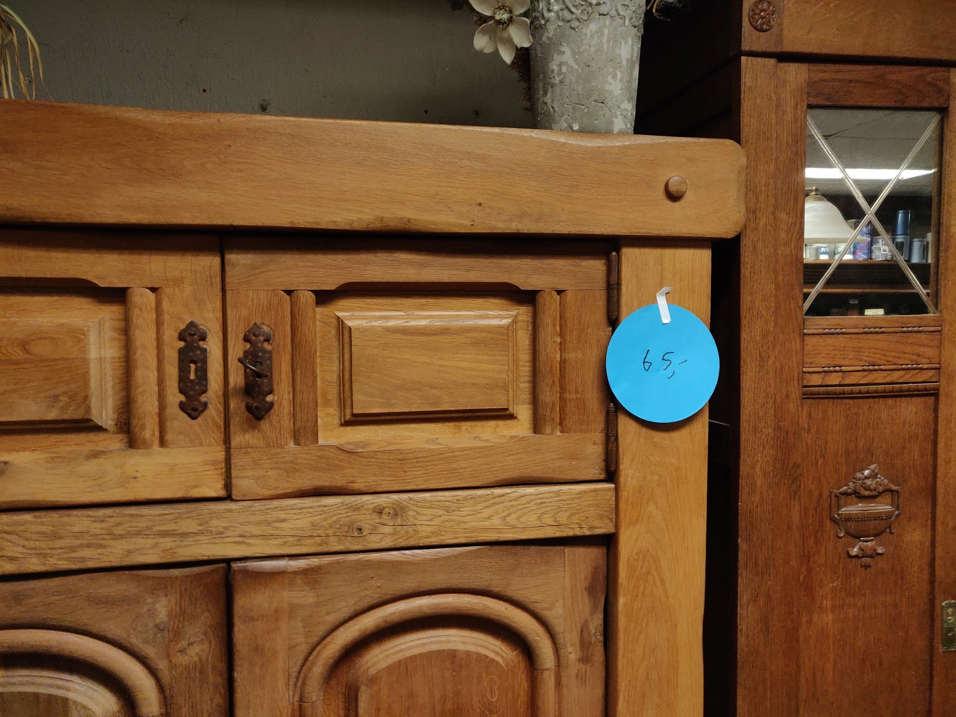 Houten kastje met decoratieve panelen en blauwe prijssticker met '65'