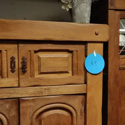 Houten kastje met decoratieve panelen en blauwe prijssticker met '65'