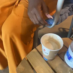 Persoon giet drank in een bekertje met logo, naast andere bekers op tafel