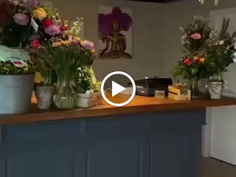 Toonbank met bloemen in vazen, Boeddhabeeldje en decoratie in een kringloopwinkel
