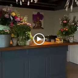 Toonbank met bloemen in vazen, Boeddhabeeldje en decoratie in een kringloopwinkel