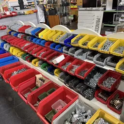 Georganiseerde stellingen met gekleurde kunststof sorteer- en opslagbakken in diverse kleuren gevuld met schroeven, bouten en