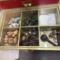 Houten organizer met zes vakken gevuld met diverse huishoudartikelen: knoflook, metalen gereedschap, witte nylon draad, houte