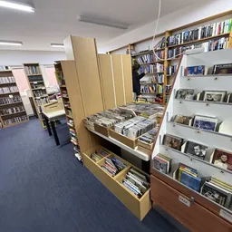 Winkelinterieur met boekenrekken, cd- en dvd-stellingen, en kartonnen displayschermen langs de winkelvloer