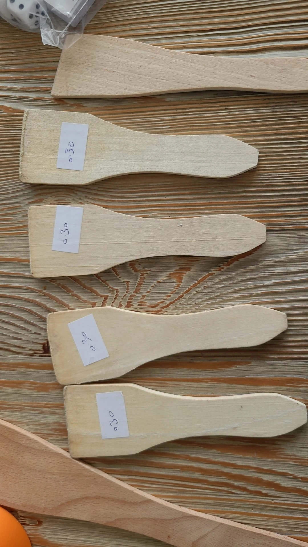 Drie houten spatelachtige keukenhulpjes met nummers 0, 3 en 0 op witte labels