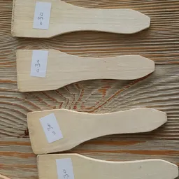 Drie houten spatelachtige keukenhulpjes met nummers 0, 3 en 0 op witte labels
