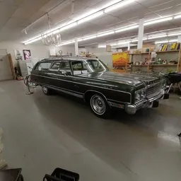 Zwarte klassieke Amerikaanse auto in een helder verlichte winkelruimte met stellingen en artikelen op de achtergrond