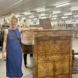 Vrouw toont houten kast met geblekte, verweerde afwerking in vintage stijl