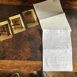 Drie gele houten miniatuurbouwsels en handgeschreven brieven op een bruine tafel