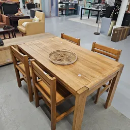 Houten eettafel met vier stoelen en een decoratief bord in het midden
