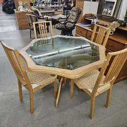 Houten eettafel met glazen blad en vier houten stoelen met beige bekleding