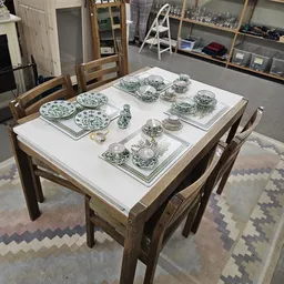 Tafel met uitgestald servies: borden, kopjes en schaaltjes met groen-wit bloempatroon