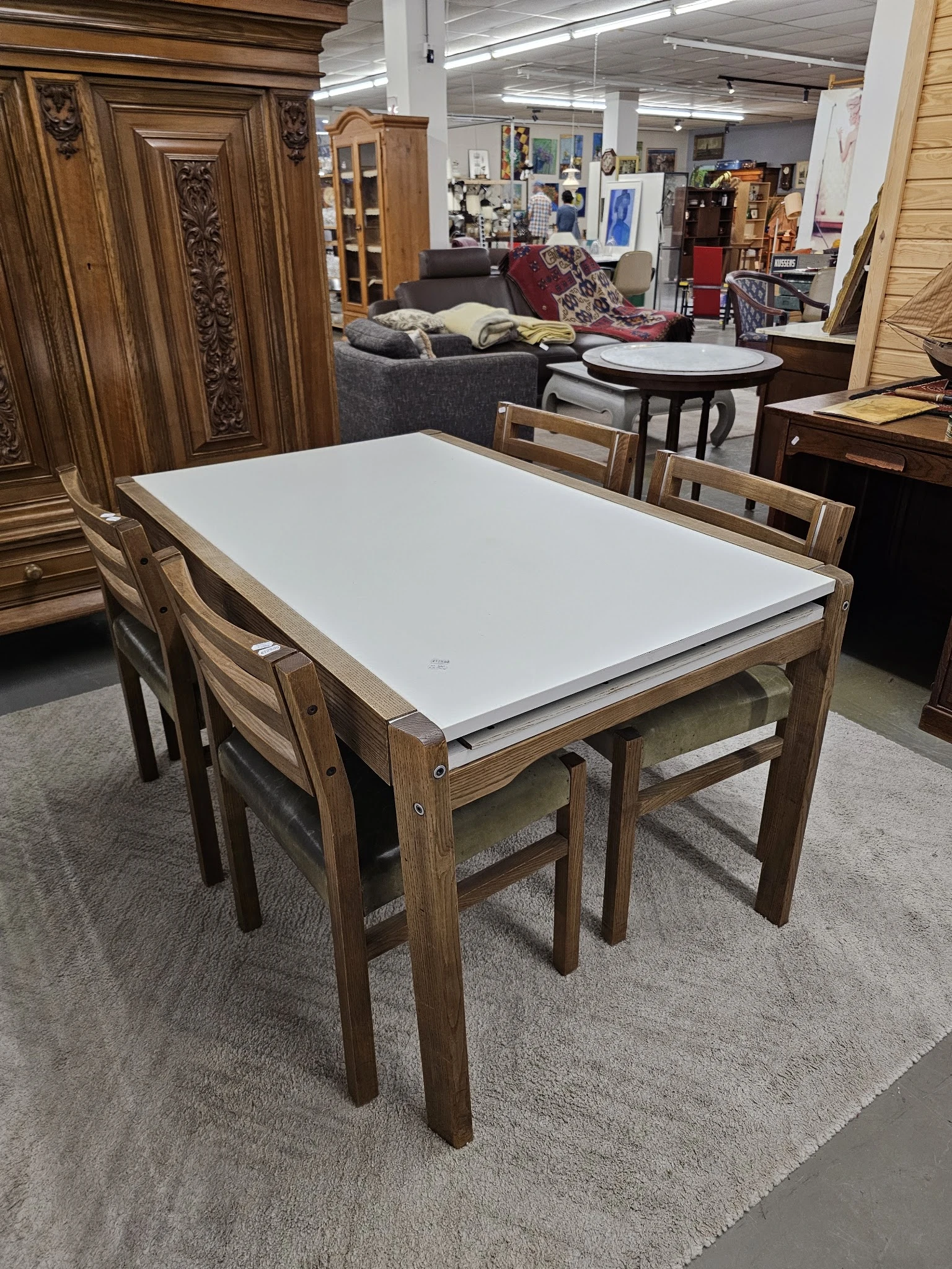 Rechthoekige houten eettafel met witte blad en bijbehorende stoelen in kringloopwinkel.