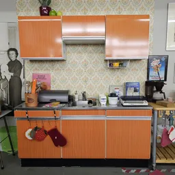 Vintage keukenhoek met oranje kasten, retro accessoires en muurdecoratie in kringloopwinkel