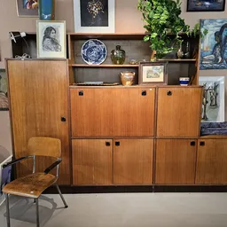 Houten vintage dressoir met meerdere kastdeuren en open schappen, voorzien van decoratieve objecten, schalen en planten.
